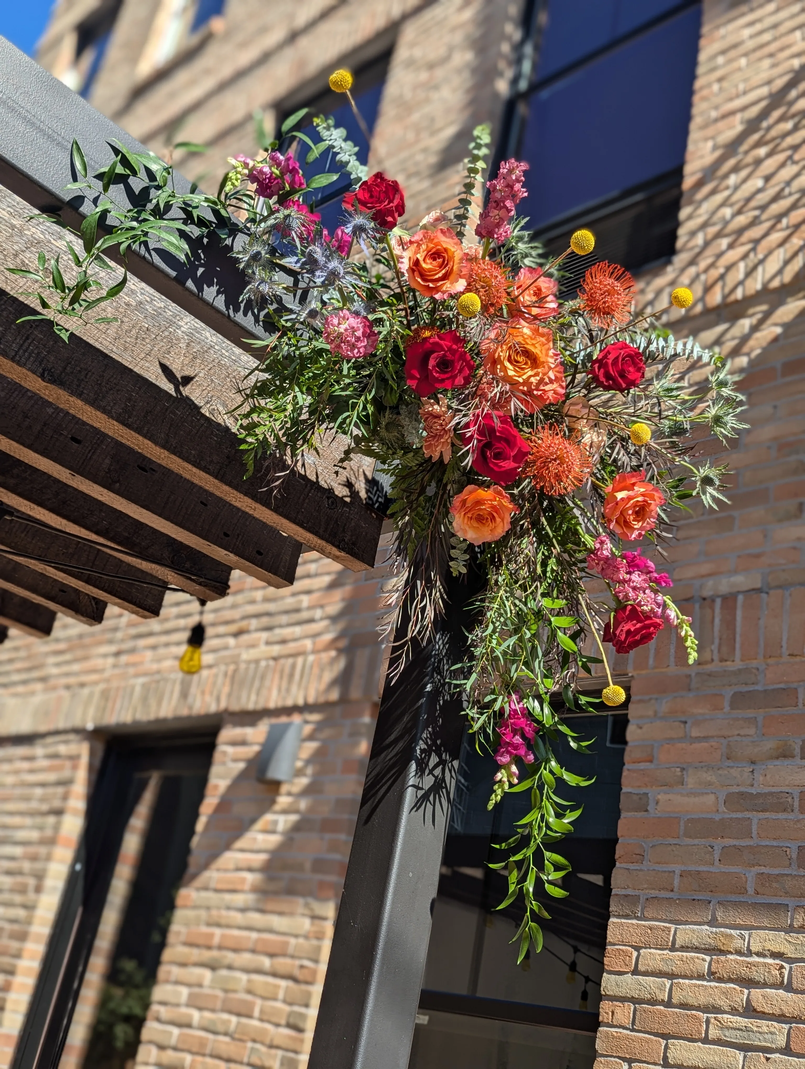 Sunlit detail of jewel-toned florals at the pergola's corner
