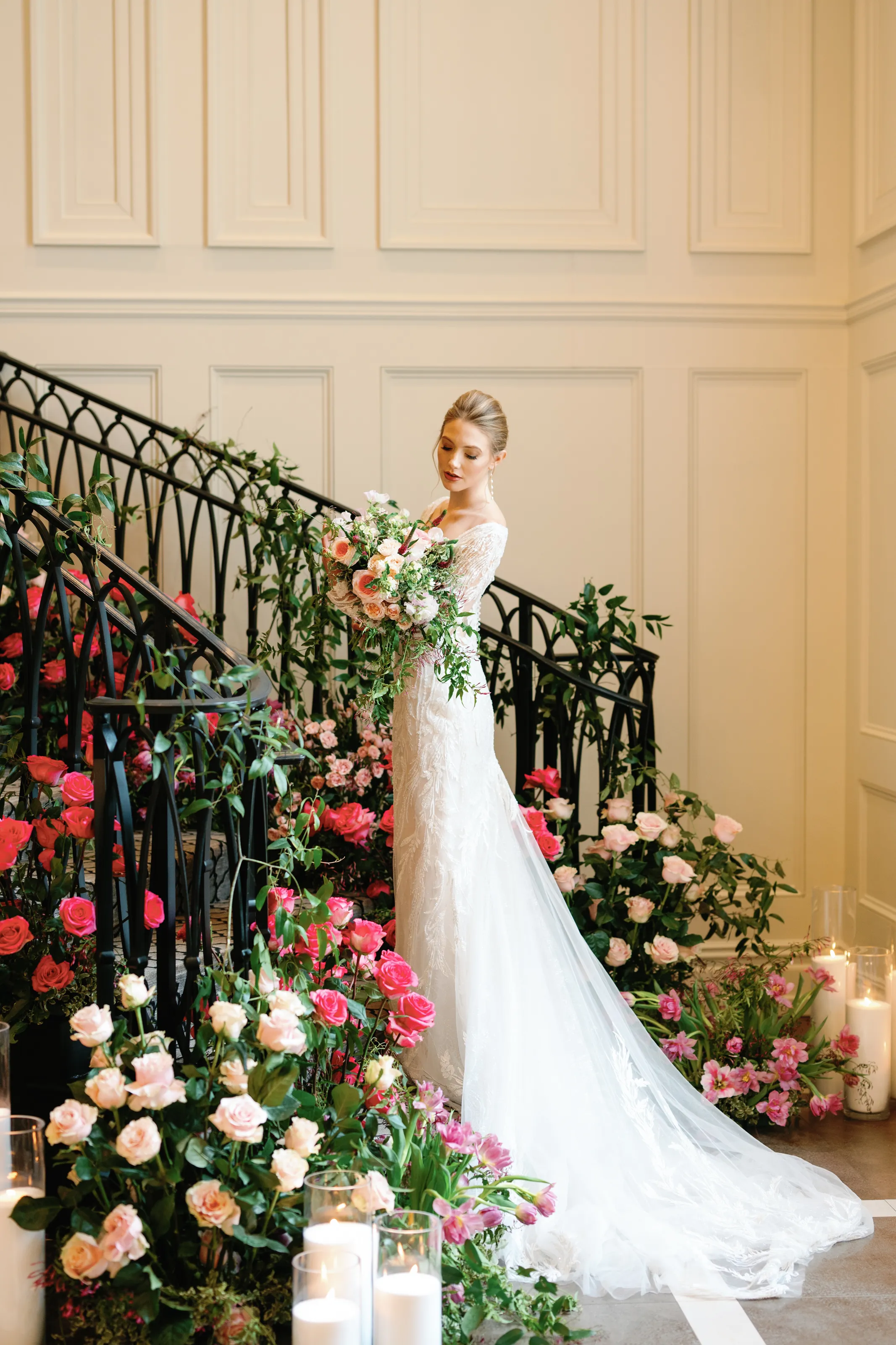 A bridal portrait on Estate at Florentine Gardens' grand staircase, its railing dressed in cascading pink and red roses