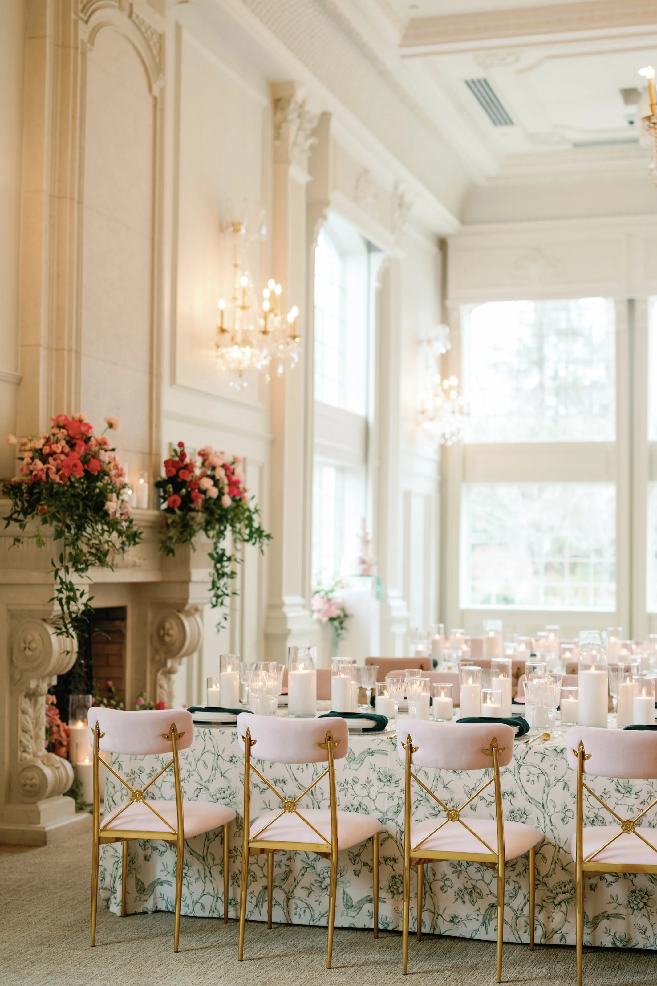 The reception room, gold and pink florals on the mantel above a table set in blush linens and candlelight