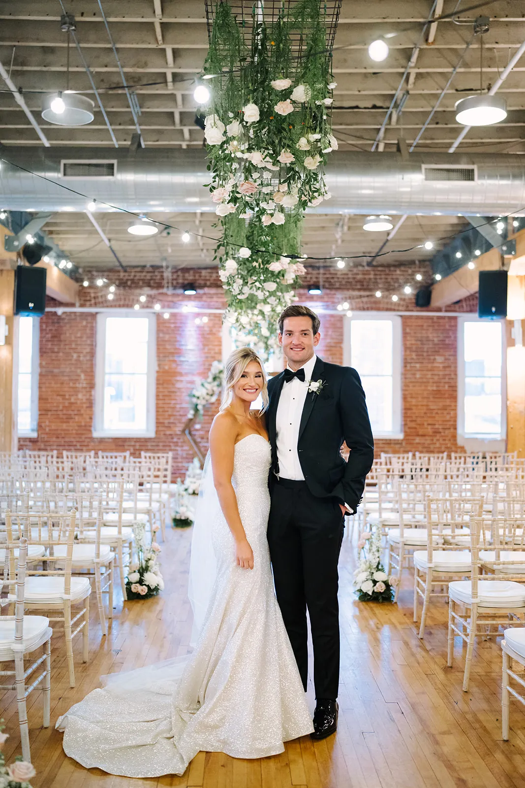 The ceremony aisle at The JX, empty chairs framed by the floral arch before guests arrive