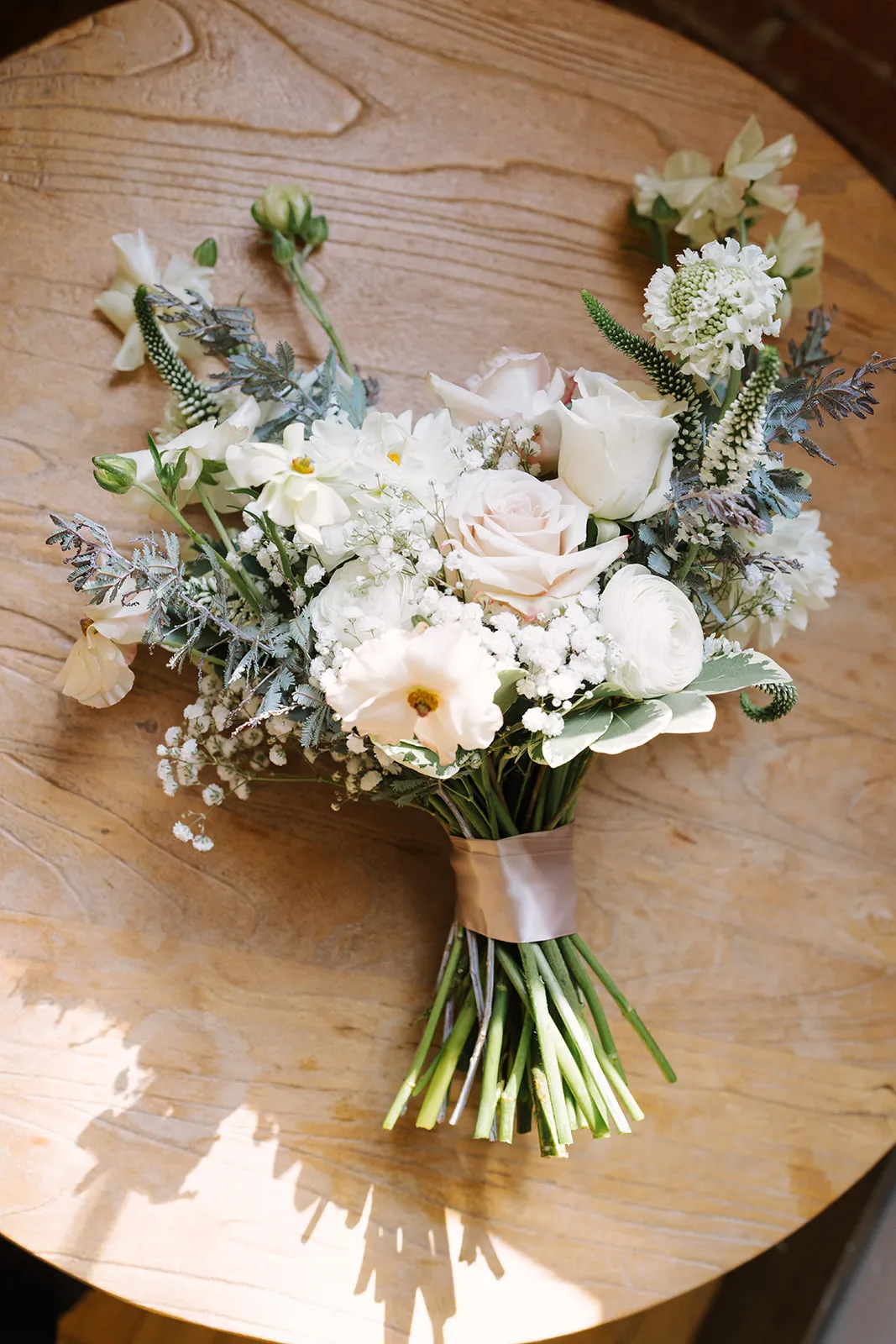 Bridal bouquet flat lay on a wood table at The JX Event Venue, Stillwater