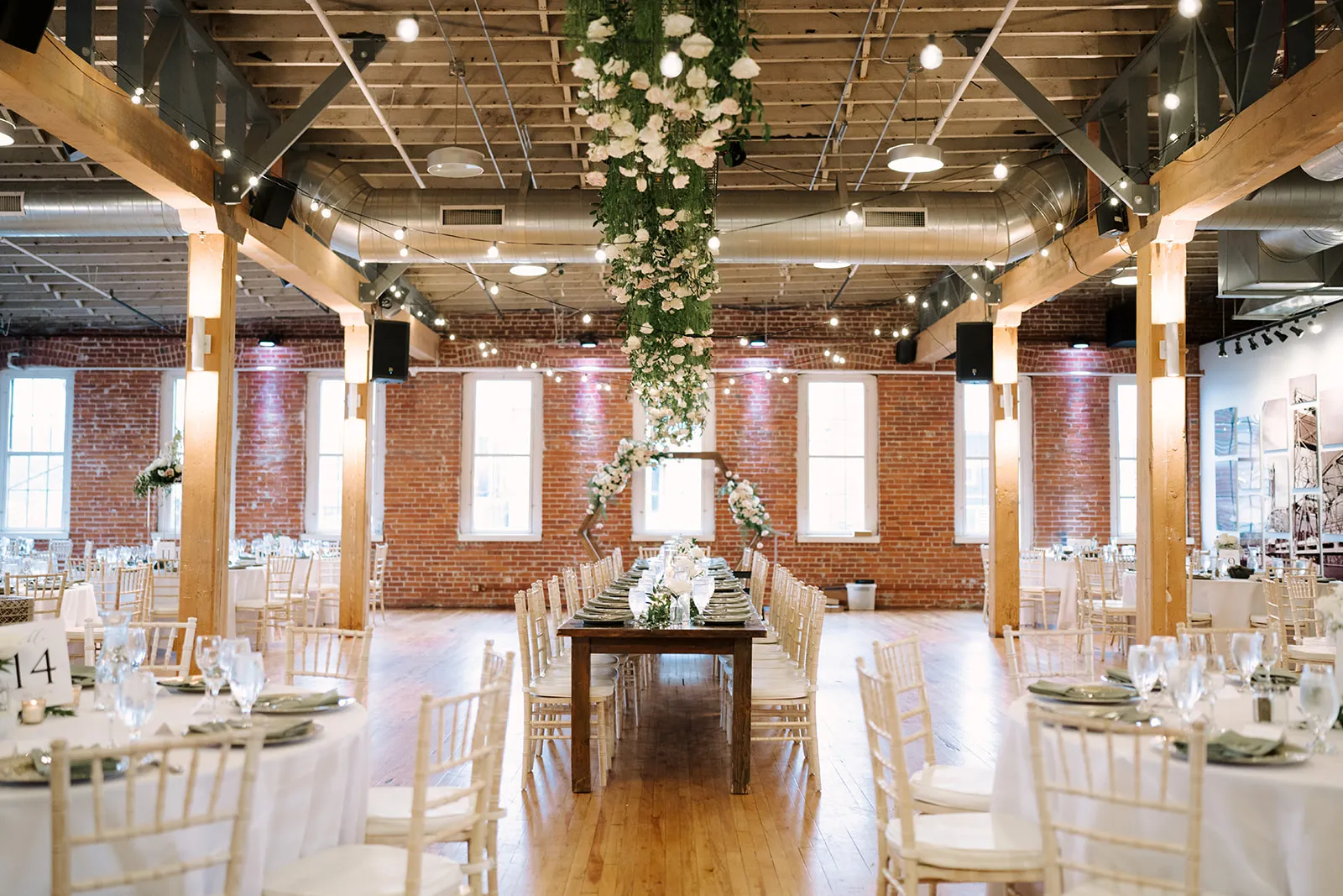 Wide view of a full reception room with long tables and floral arrangements at The JX Event Venue, Stillwater
