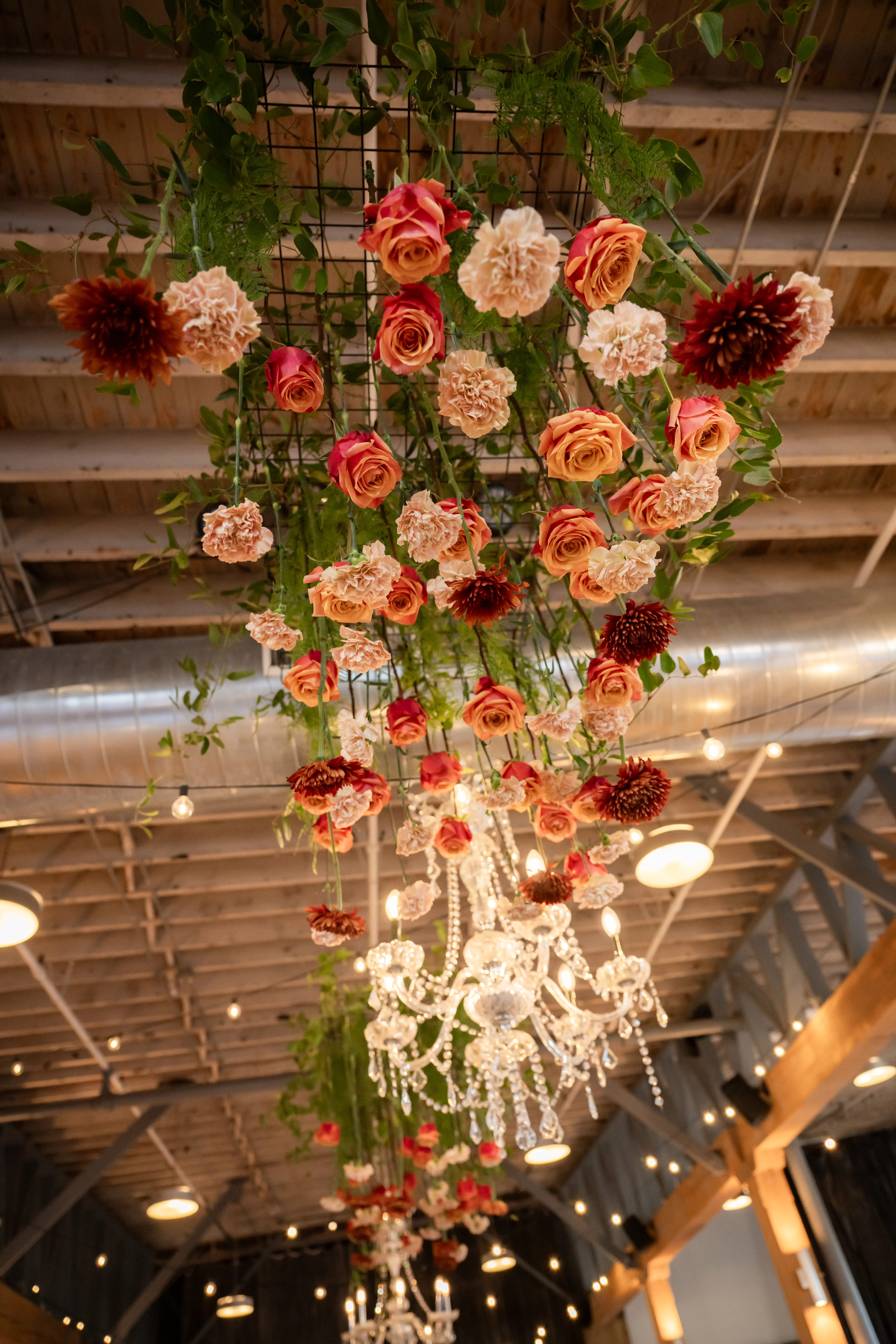 Detail of the hanging floral chandelier, roses and carnations suspended above the room
