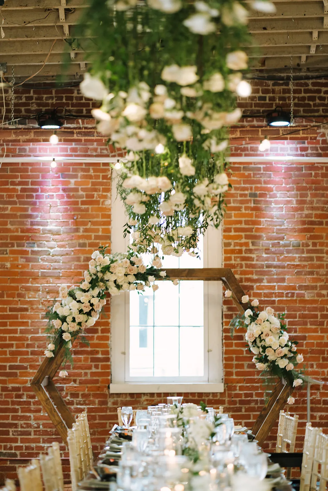 The hexagon arbor and hanging floral installation reset behind the reception tablescape