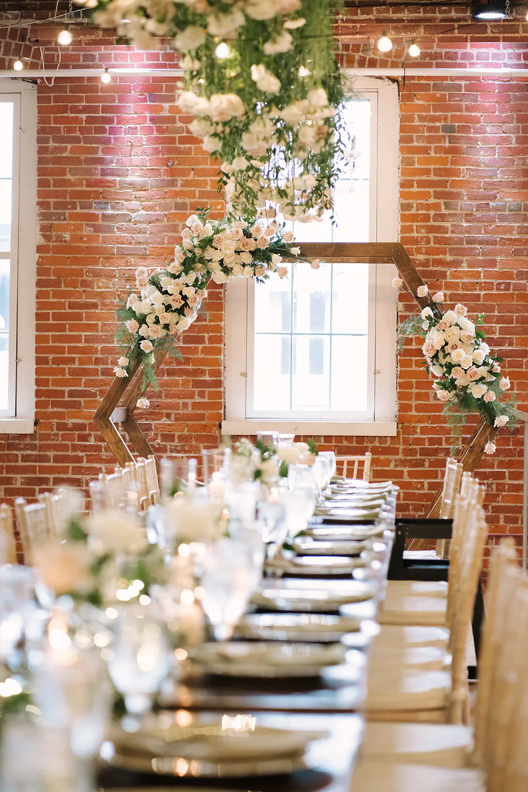 Wide view of the reception tablescape with the repurposed hexagon arbor as backdrop
