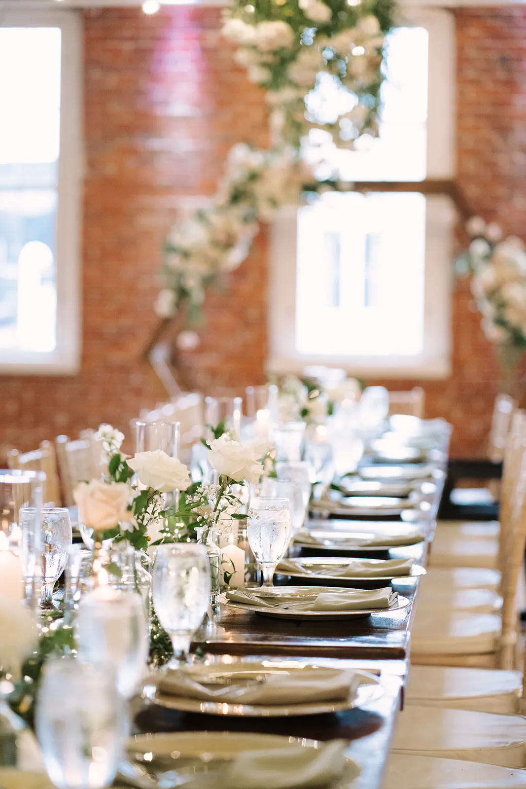 Long reception table with place settings and floral arrangements at The JX Event Venue, Stillwater