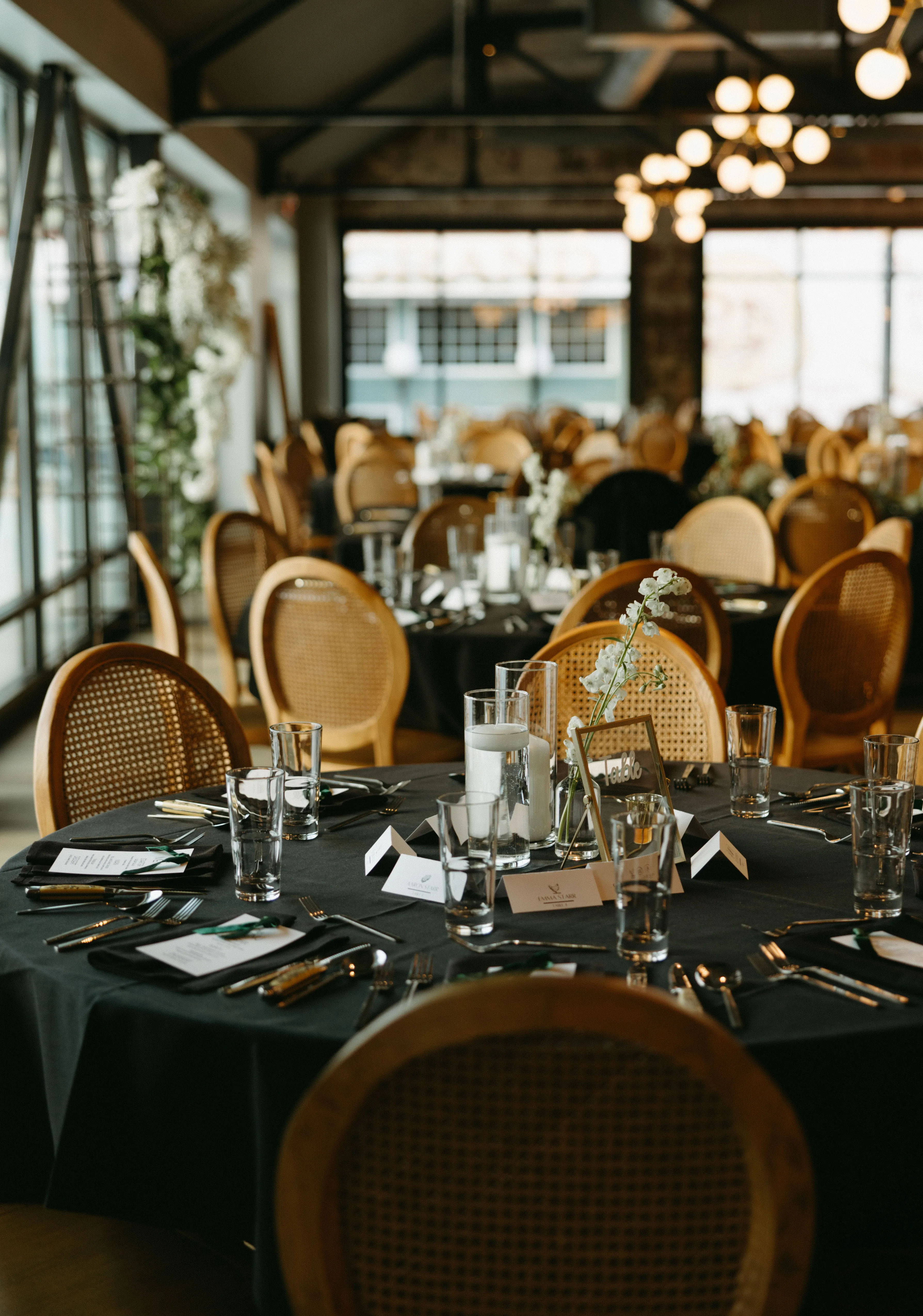 The Lora's reception dining room set for the evening, cane-back chairs and candlelight around each table