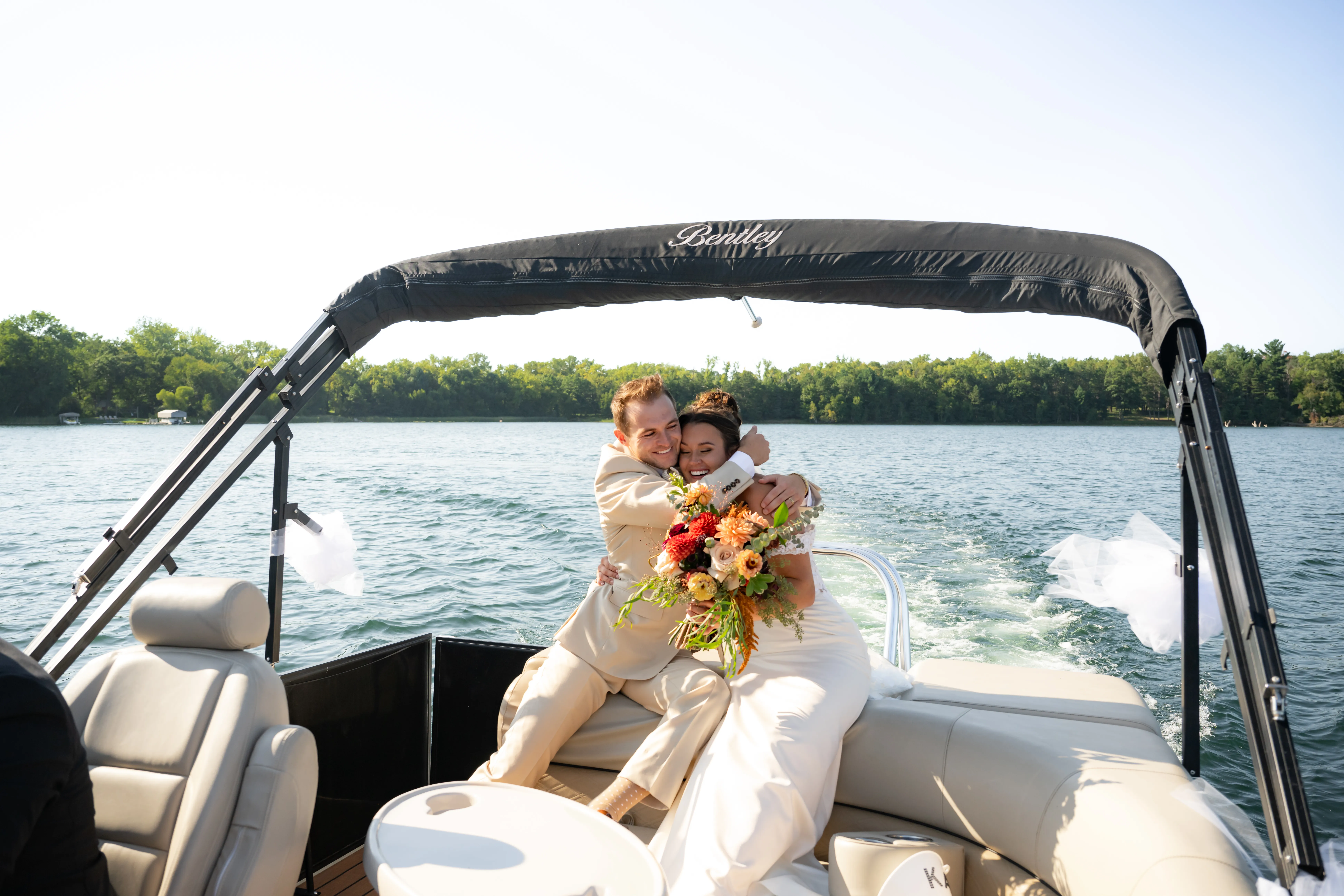 An embrace aboard the pontoon boat, the lake stretching out behind them