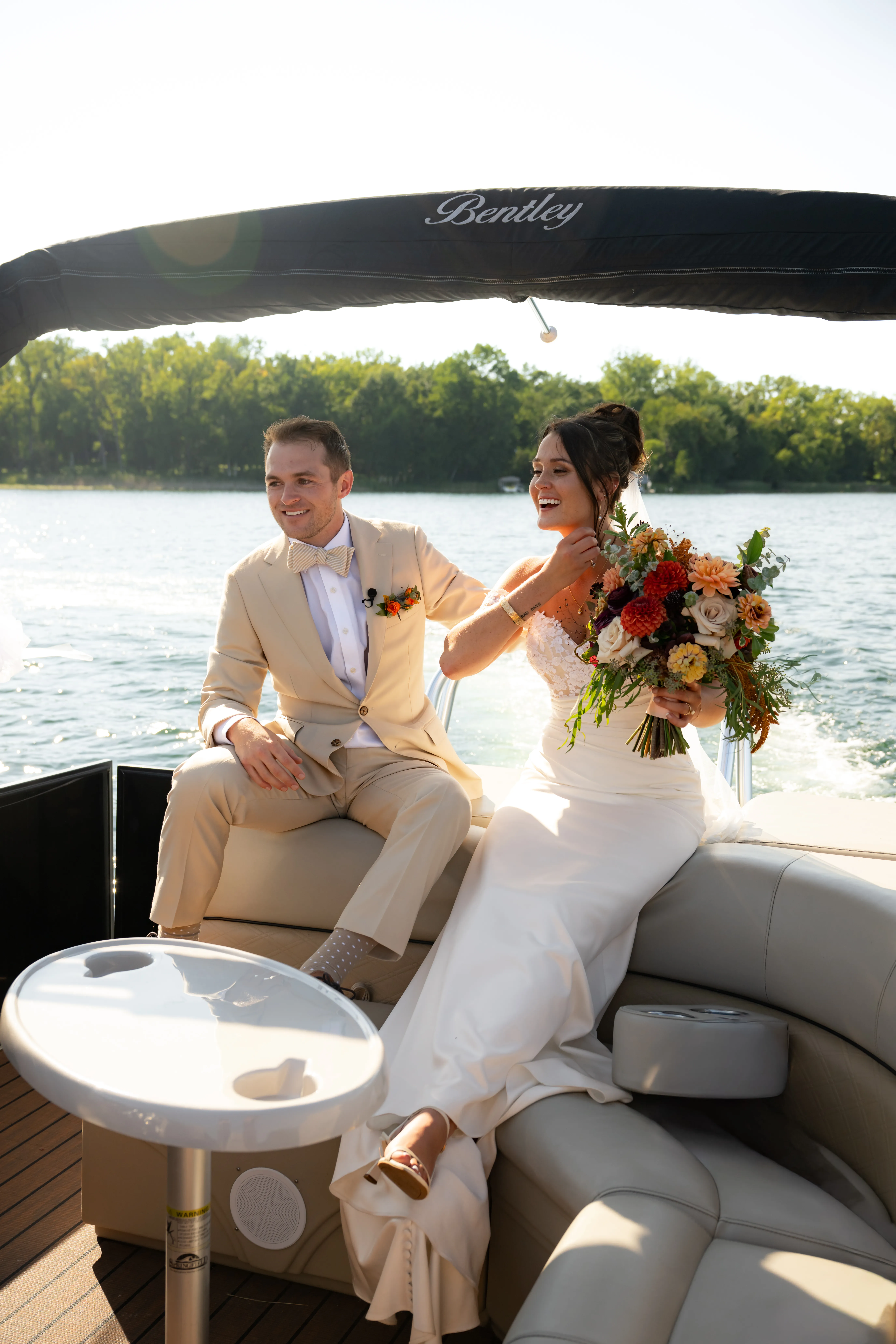 Katie and Kurt aboard a pontoon boat on the lake, bouquet in hand
